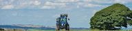 Blue tractor travelling along field