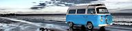 Blue and white Volkswagen campervan parked on costal road with tide out