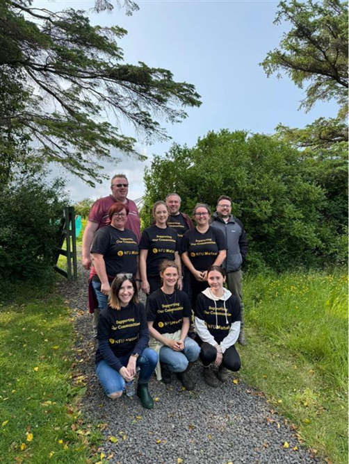 A group of NFU Mutual employees engaging in voluntary work, wearing matching black T-shirts with "Supporting Our Communities" written on in yellow.