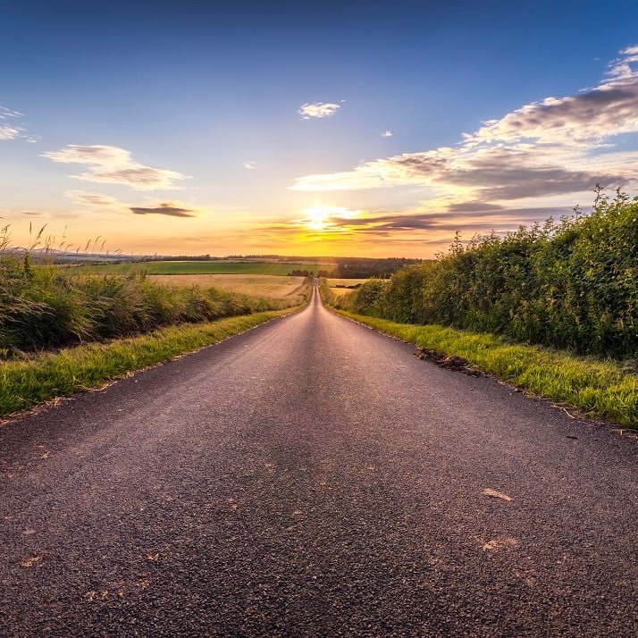 Country road leading to sunset on horizon