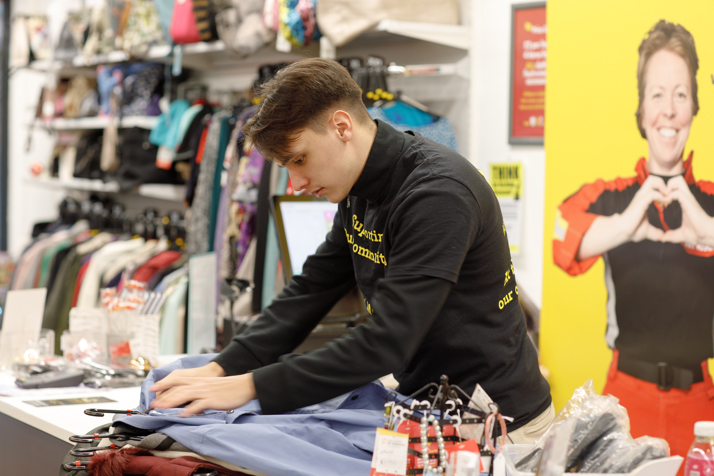 A volunteer working at a charity shop at the till