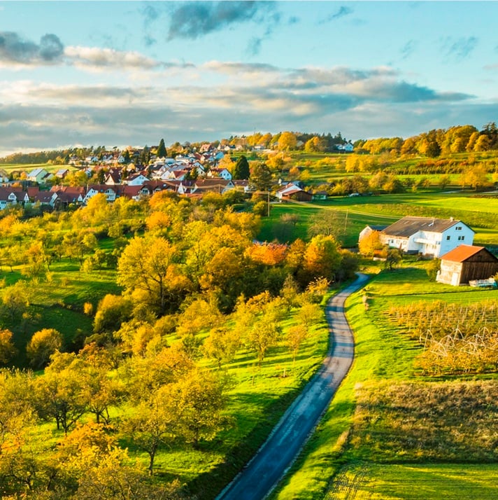 Rural community landscape on a sunny date with fields in the foreground and houses in the background