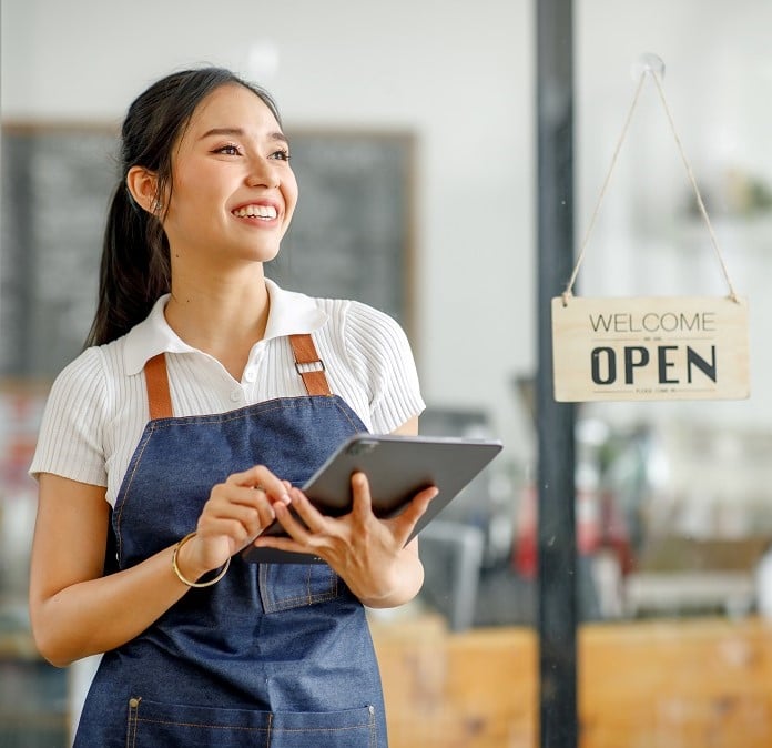 shop owner in front of of open sign 