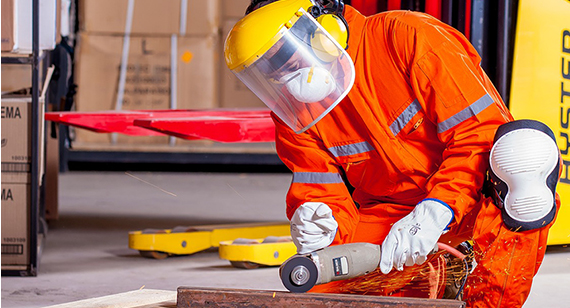 Worker wearing personal protection equipment and high visibility jacket using angle grinder