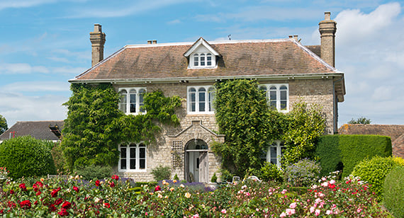 Rural mass affluent stone home with rose flowerbeds in foreground