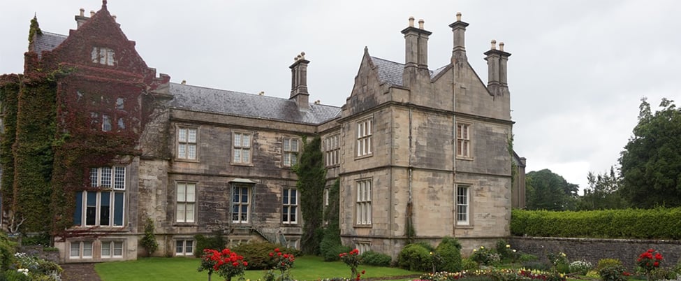 Large stately home with flower beds in foreground
