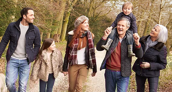 Family of 4 adults and 2 children walking their dog in a woods